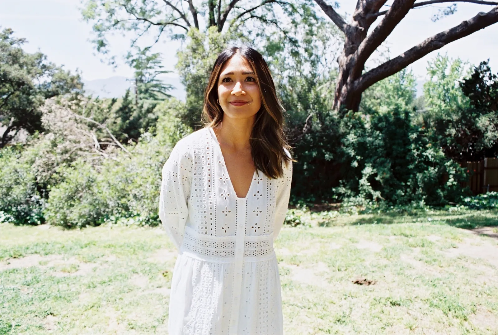 A woman standing in a garden, looking toward the camera